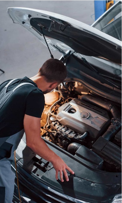 Technician working beneath an open car hood